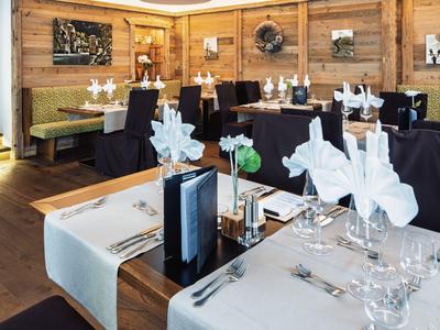 Elegant restaurant met gedekte tafels, zwarte stoelen en houten muren op de achtergrond.