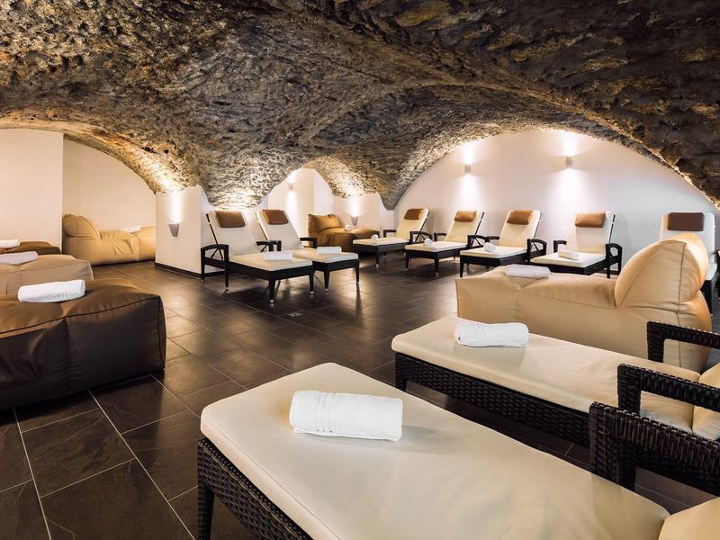 Entspannungsbereich mit bequemen Liegen und sanfter Beleuchtung in einem gewölbten Raum.