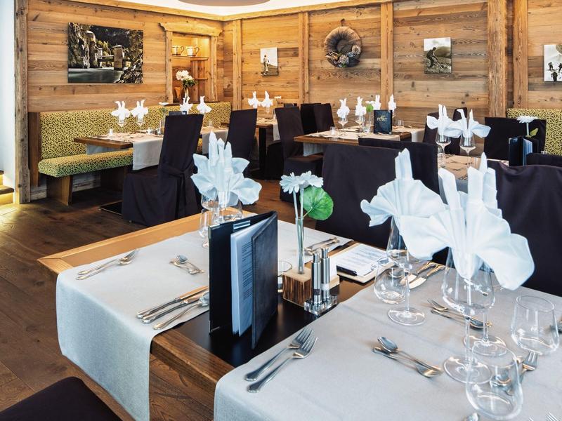 Elegantes Hotelrestaurant mit stilvoll gedeckten Tischen und Holzwänden.