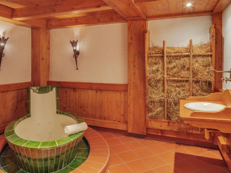 Rustikales Badezimmer mit grüner runder Badewanne, Holzwänden und Heu als Deko.