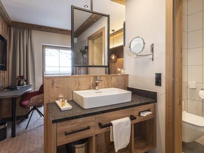 Modernes Hoteldoppelzimmer mit Bad, Waschbecken, Schreibtisch und Fernseher.