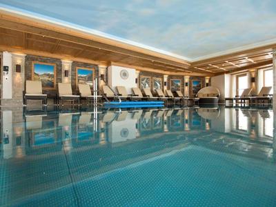 Hell beleuchteter Innenpool mit Liegestühlen und Holzdach in einem Hotel