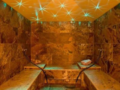 Ein luxuriöser Wellnessbereich mit Marmorwänden, Bänken und einem beleuchteten Whirlpool.