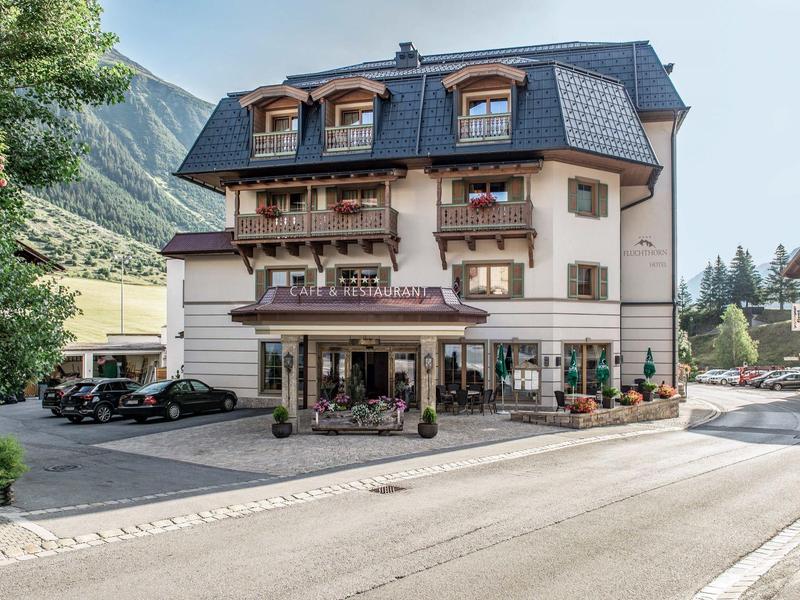 Drei-geschossiges Hotelgebäude mit Balkon und Bergblick in einer ruhigen Straße.
