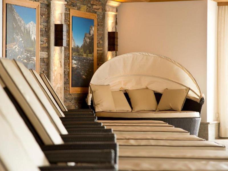 Schlichte Liegestühle in einem warm beleuchteten Wellnessbereich mit runden Korbsofa.