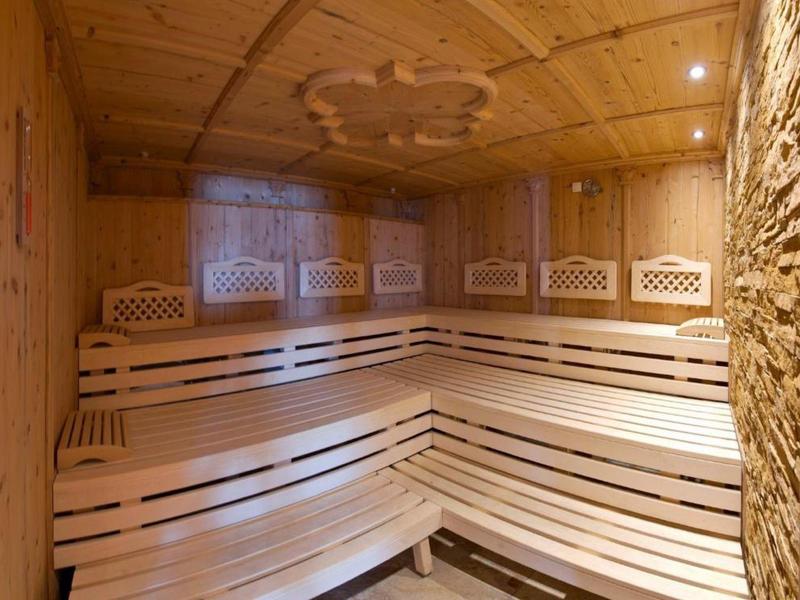 Innenraum einer Sauna mit Holzbänken und Wandverkleidung aus Holz und Stein.