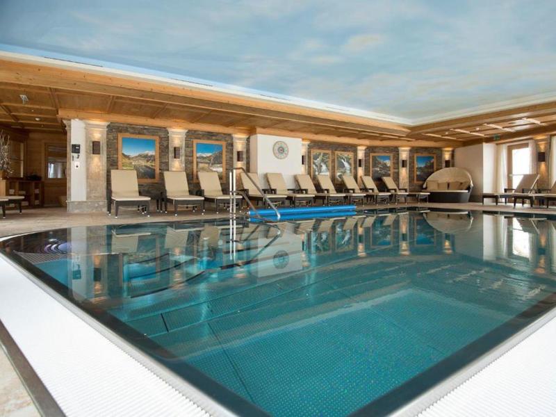 Innenpool in einem luxuriösen Hotel mit Liegestühlen und großen Fenstern.