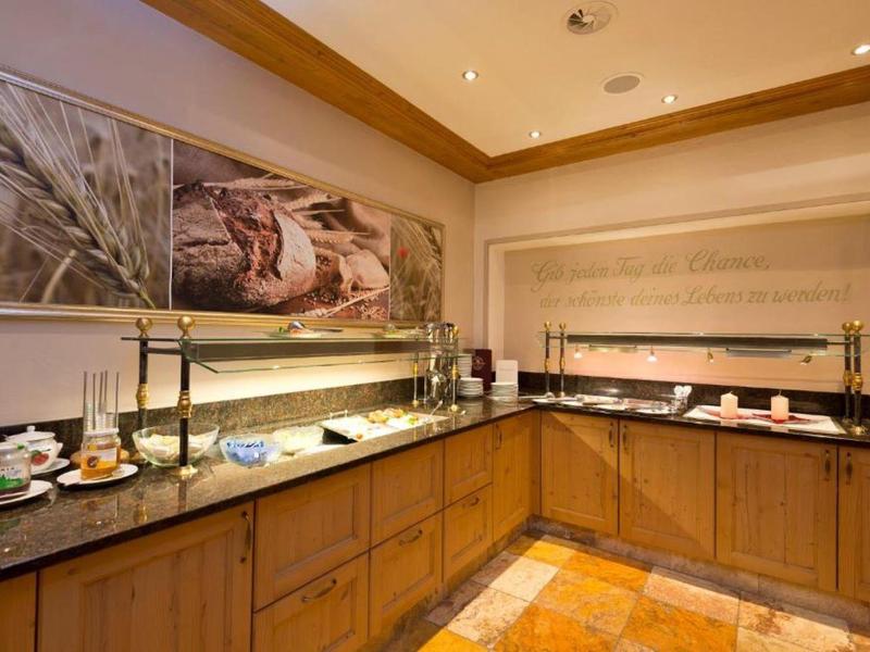 Buffetbereich mit Holzschränken, Kaffee- und Teeangebot sowie einer großen dekorativen Wandkunst.