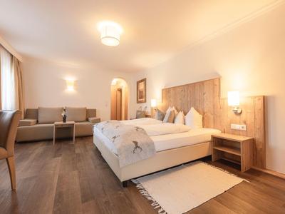 Modernes Hotelzimmer mit großem Bett, Sesseln und warmem Holzboden