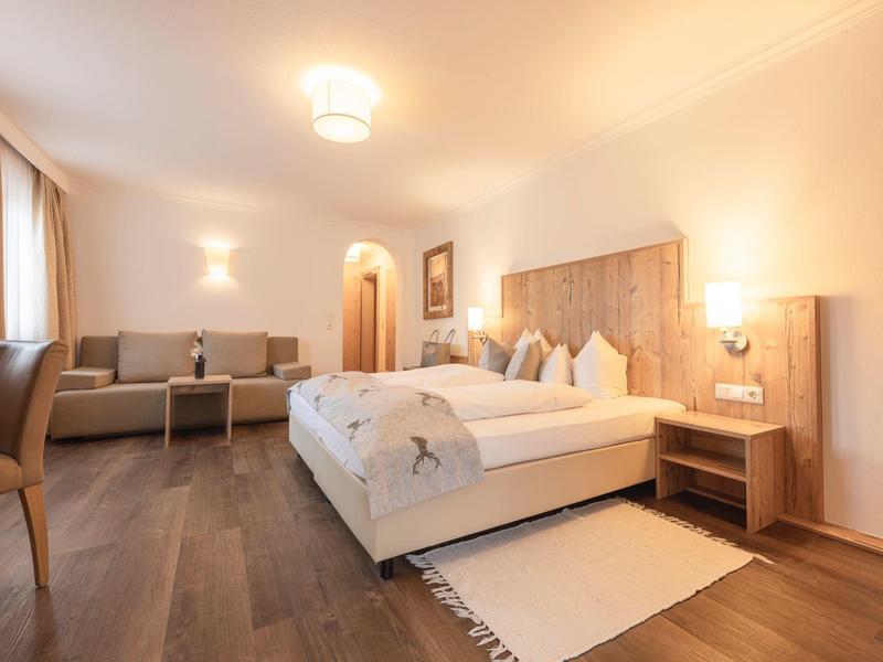 Modernes Hotelzimmer mit großem Bett, Sesseln und warmem Holzboden