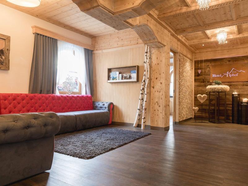 Gemütlicher Hotel-Lounge-Bereich mit Holzwänden, rotem Sofa und dunklem Teppich.