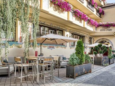 Attractive outdoor café terrace with tables, chairs, umbrellas, and flowers on the facade.