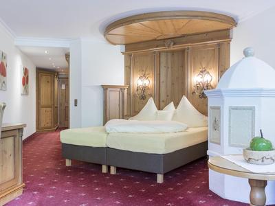 Gemütliches Hotelzimmer mit Doppelbett, Teppichboden und traditionellem Ofen.