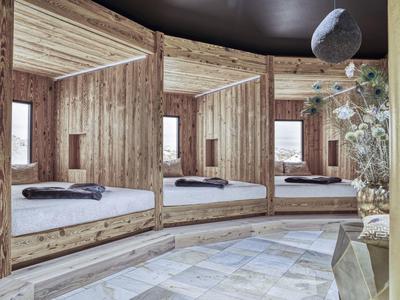 Gemütliches Rundbett mit Holzwänden und Blick auf Holzboden und Deko im Raum.