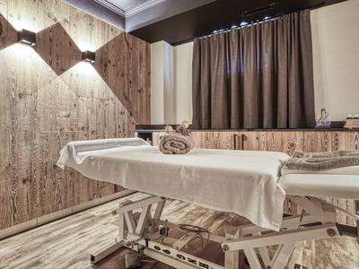 Behandlungsraum mit Massagetisch, Holzwänden und gedämpftem Licht.