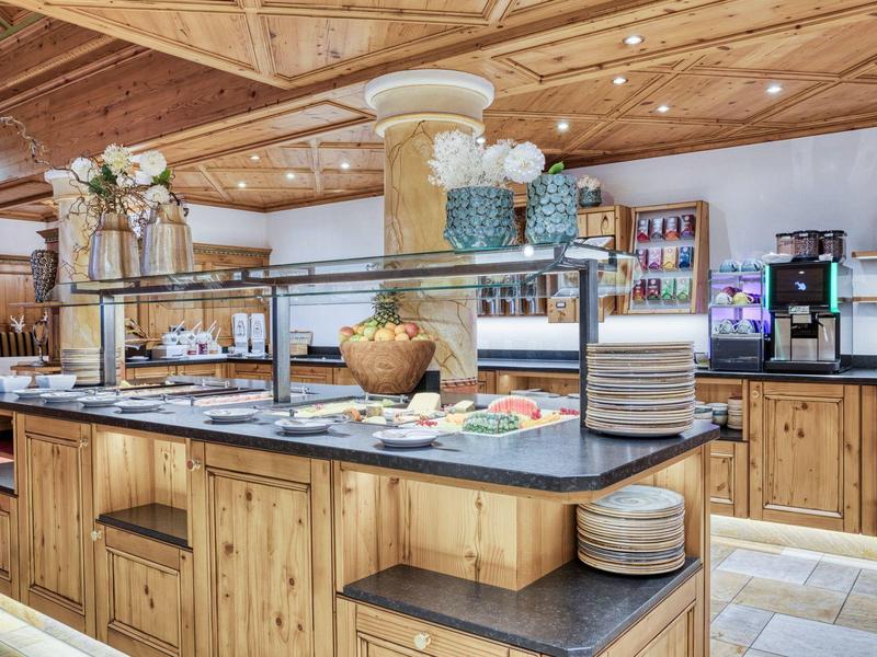 Buffetbereich mit verschiedenen Speisen und hölzernen Möbeln in einem Restaurant oder Hotel.