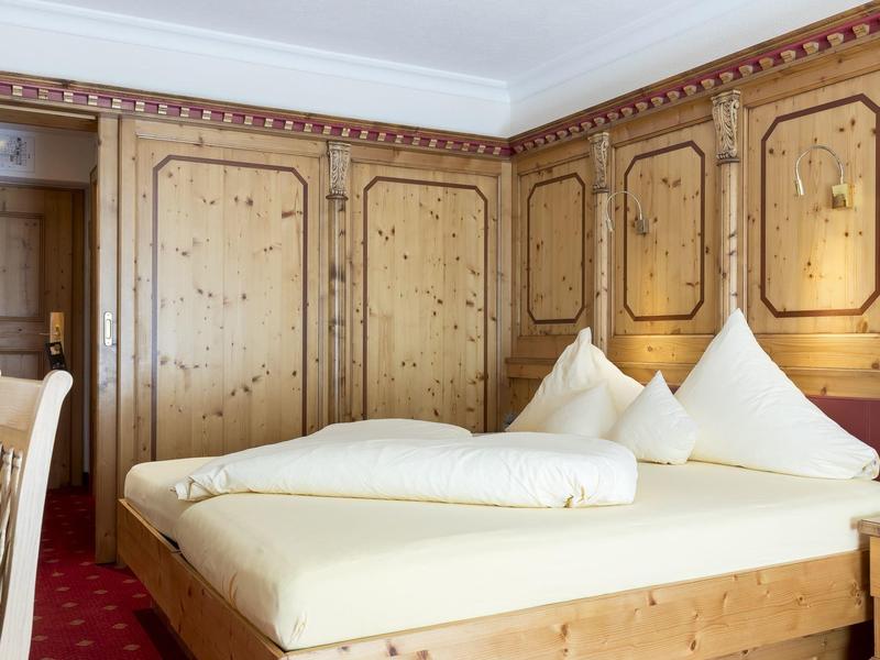 Ein einfaches Hotelzimmer mit Holzwänden, Doppelbett und rotem Teppichboden.