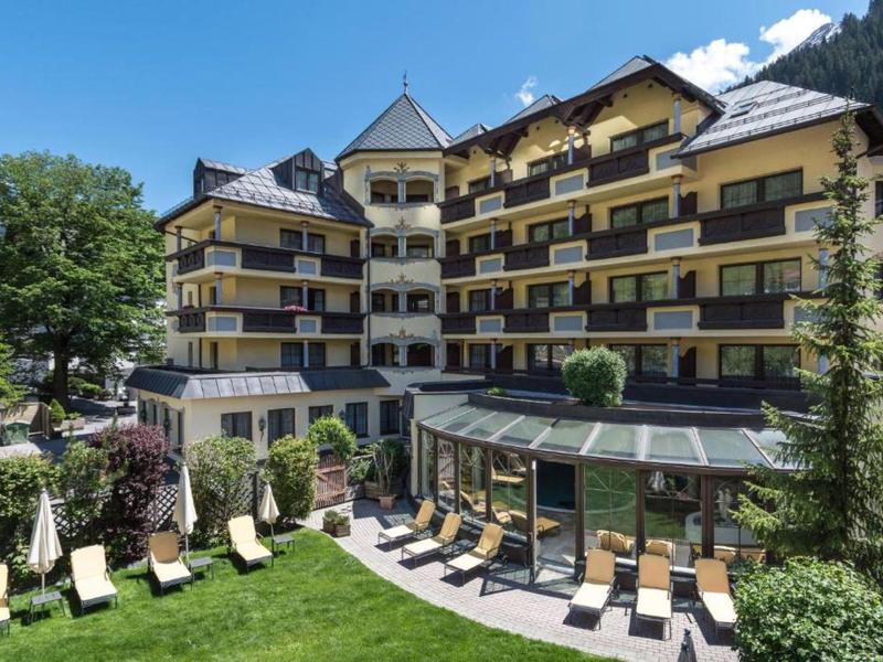 Mehrstöckiges Hotelgebäude mit Balkonen und Sonnenterrasse in grüner Umgebung