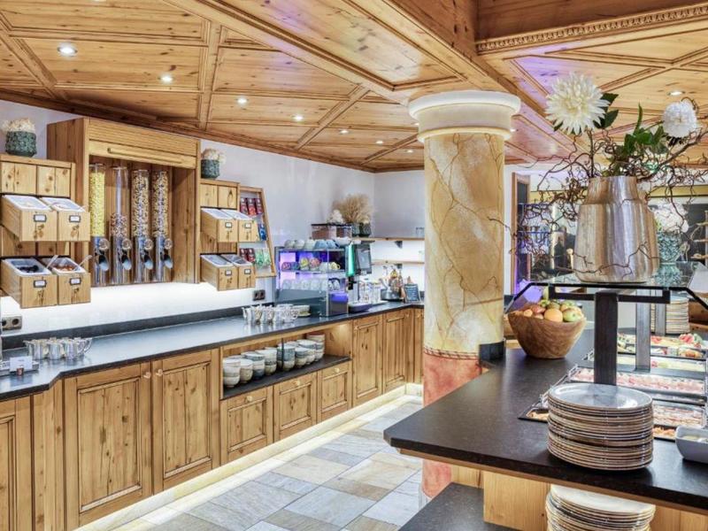 Gemütlicher Frühstücksraum mit Holzverkleidung, Buffet und frischen Blumen.