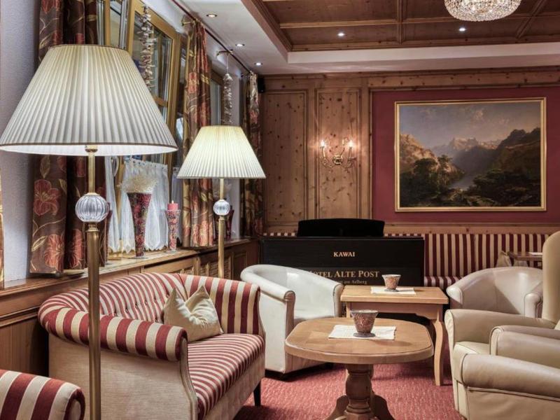 Elegantes Wohnzimmer mit Holzvertäfelung, bequemen Sesseln und einem Klavier vor Gemälden.