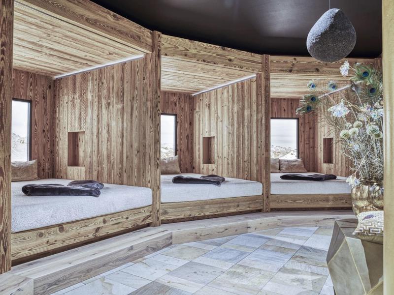 Gemütliches Rundbett mit Holzwänden und Blick auf Holzboden und Deko im Raum.