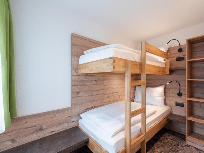 Small room with bunk bed, wooden paneling, and open shelving on the wall