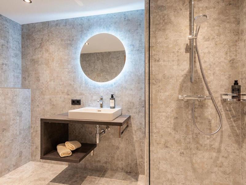 Modern bathroom with bright sink, round mirror, and walk-in shower.