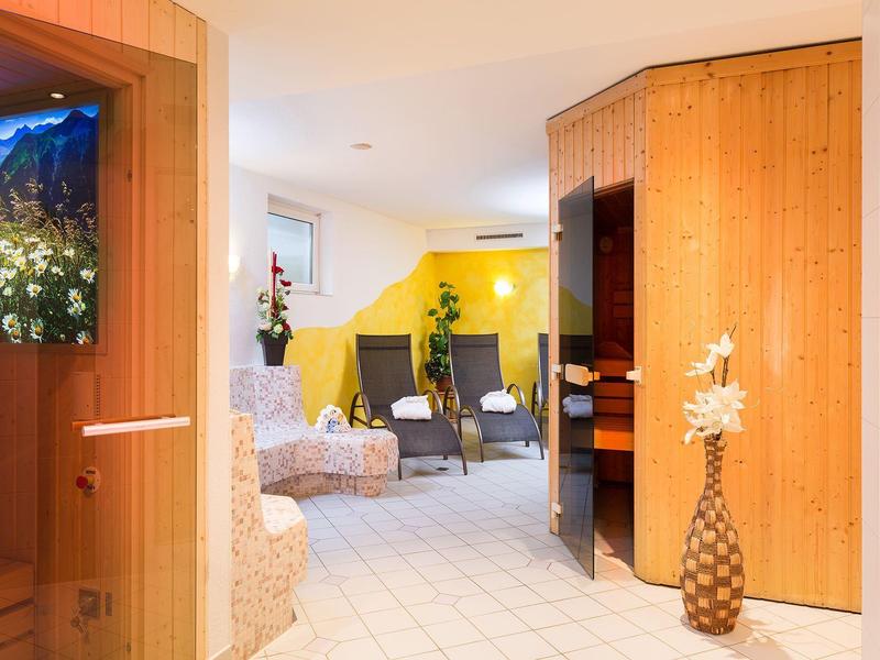 Cozy wellness area with sauna room, loungers, and floral decorations in warm wood tones.