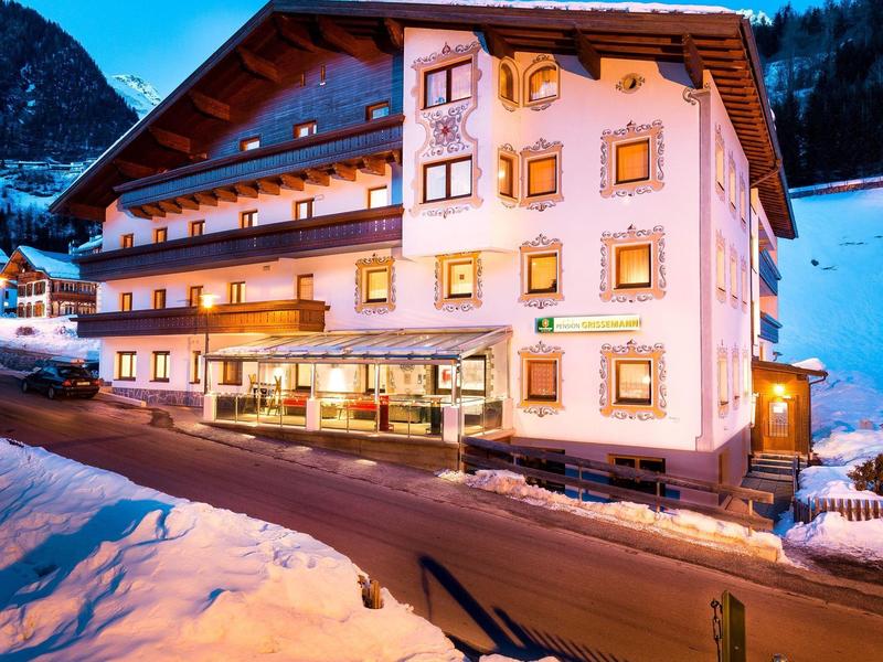 Large hotel building in snowy mountains at dusk.