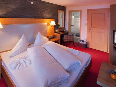 Gemütliches Hotelzimmer mit Doppelbett, Nachttischen und warmem Licht.