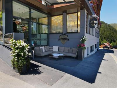 Modernes, überdachtes Außensitzbereich mit Sofas und Hängelampe an einem Hotel.