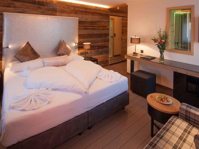 Gemütliches Hotelzimmer mit großem Bett, Holzwand und modernem Schreibtisch.