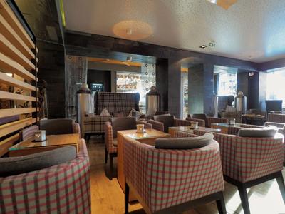 Gemütlicher Hotel-Loungebereich mit karierten Sesseln und gedämpftem Licht.