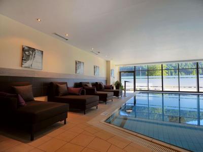 Moderner Innenpool mit großen Fenstern und gemütlichen Sitzbereichen