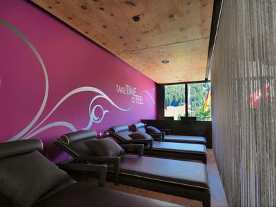 Moderner Ruheraum mit Liegen, violetter Wandgestaltung und Vorhängen in einem Hotel.