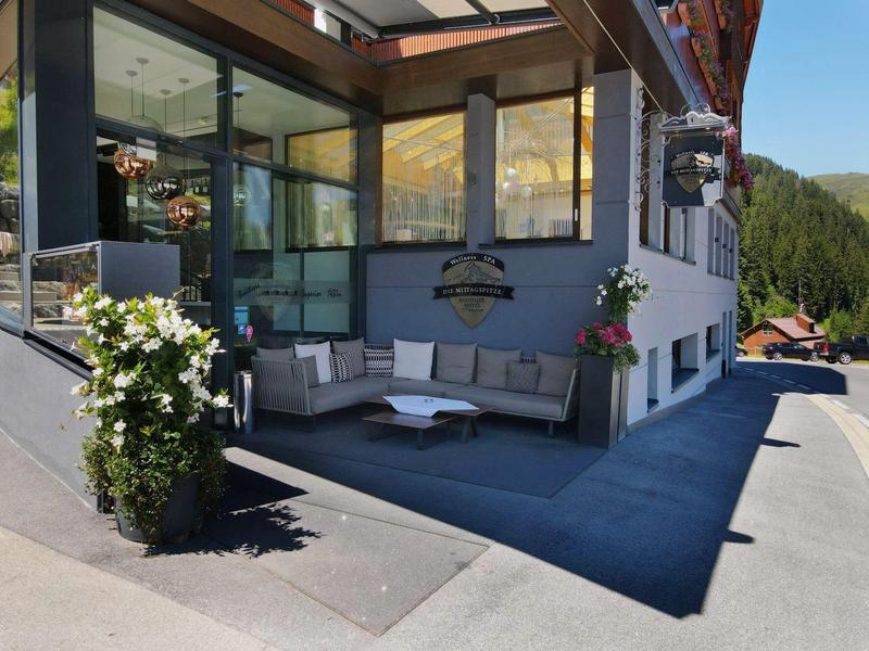 Modernes, überdachtes Außensitzbereich mit Sofas und Hängelampe an einem Hotel.