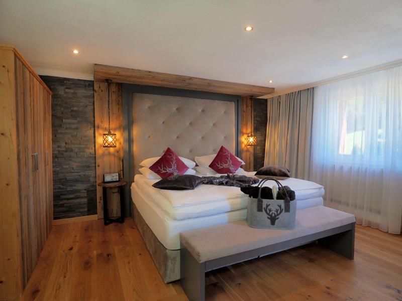 Gemütliches Hotelzimmer mit Doppelbett, Holzboden und warmen Beleuchtungselementen.