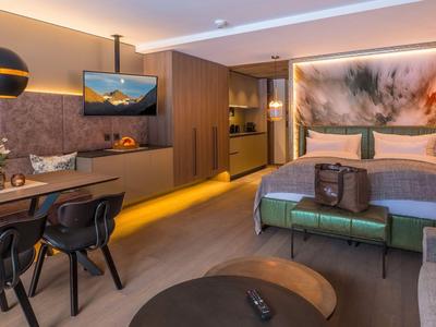 Modern hotel room with double bed, workspace, and television.