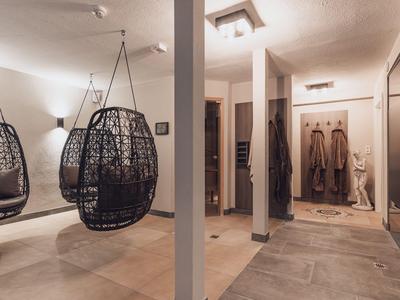 Modern room with two hanging black wicker chairs and gray stone floor