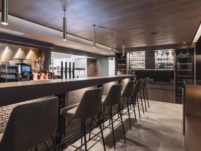 Moderner Hotelbarbereich mit hohem Tresen, Barhockern und warmbeleuchtetem Ambiente.