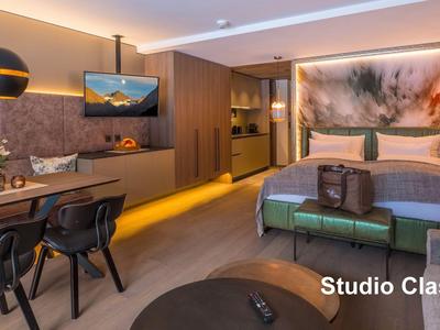 Modern eingerichtetes Hotelzimmer mit Bett, TV und Schreibtisch in warmen Farben.