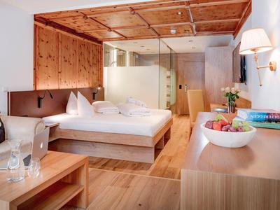 Helles Hotelzimmer mit Holzverkleidung, Doppelbett, gemütlicher Atmosphäre und modernen Annehmlichkeiten.