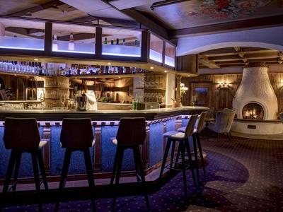 Gemütliche Bar mit Holzmöbeln und Kamin in einem Hotelambiente bei gedämpftem Licht.