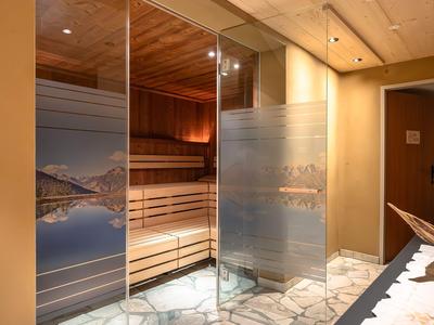 Moderner Sauna-Eingang mit Glas-Schiebetüren und Natursteinboden in einem Hotel.