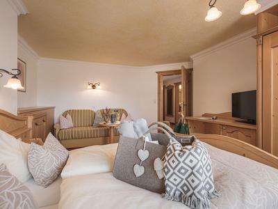 Gemütliches Hotelzimmer mit Doppelbett, Sofa, Holzmöbeln und Fernseher.