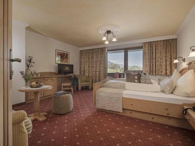 Gemütliches Hotelzimmer mit Doppelbett, Teppichboden und Balkon mit Bergblick.