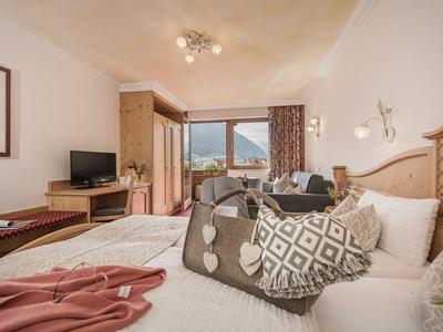 Helles Hotelzimmer mit großem Bett, komfortablen Kissen und Blick auf die Berge.