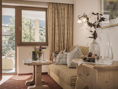Gemütliche Hotellounge mit Sofa, Tisch, Dekoration und Blick auf Balkon und Berge.