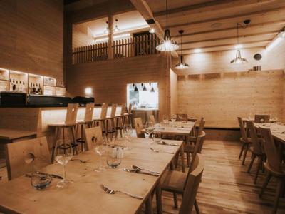 Modernes Restaurant mit Holzmöbeln und gedämpfter Beleuchtung in warmen Tönen.