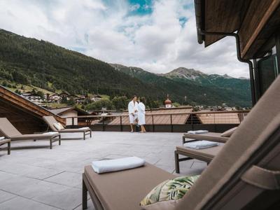 Terrasse mit Liegestühlen und Bergblick an einem Hotel in den Alpen.